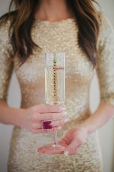 a woman holding a wine glass in one hand and wearing a ring on the other