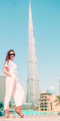 a woman standing in front of the burj building, with sunglasses on her face