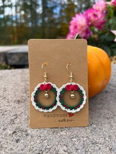 a pair of earrings sitting on top of a card next to some pumpkins and flowers