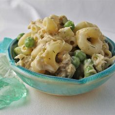 a blue bowl filled with macaroni and peas on top of a white table