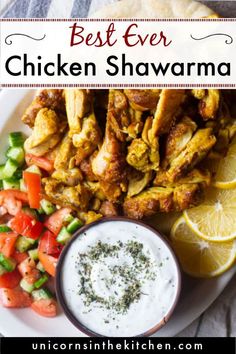 the best ever chicken shawarma is served on a white plate with lemon wedges, cucumbers and tomatoes