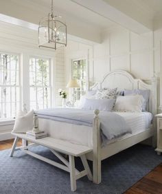 a white bed sitting on top of a wooden floor next to a blue and white rug