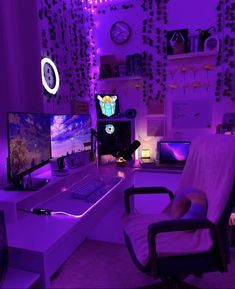 a room with purple lighting and two computer monitors on the desk, one is turned on