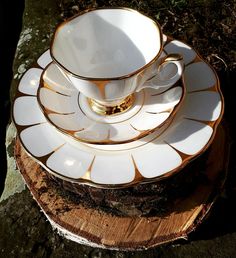 a stack of white and gold dishes sitting on top of a tree stump