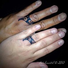 two people's hands with matching rings and tattoos on their fingers, both holding each other