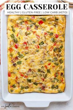 a square casserole dish filled with vegetables and cheese on a white tablecloth