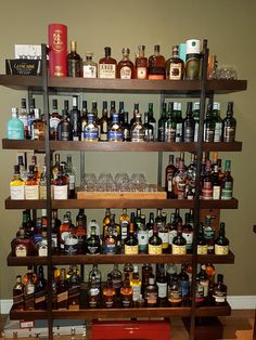 a shelf filled with lots of different types of liquor bottles and glasses on top of wooden shelves