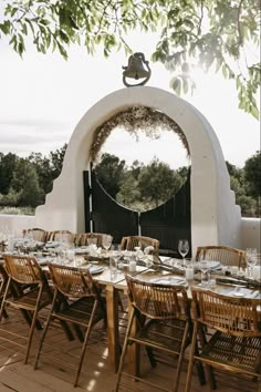 an outdoor dining table set up with place settings and wine glasses in front of it