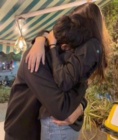 two people hugging each other under a tent