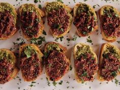 several pieces of bread with various toppings on them and sprinkled with parsley