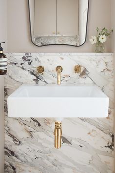 a white sink sitting under a bathroom mirror next to a wall mounted faucet