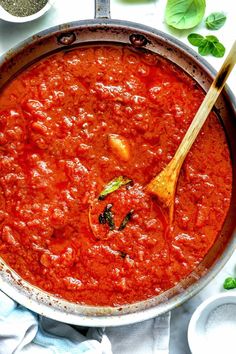 a pan filled with sauce and wooden spoon