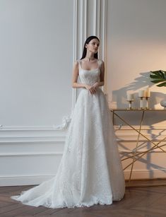 a woman standing in front of a white wall wearing a wedding dress