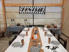 a table set up with black and white checkered paper plates, napkins and place settings