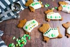 several decorated cookies sitting on top of a wooden table next to green sprinkles