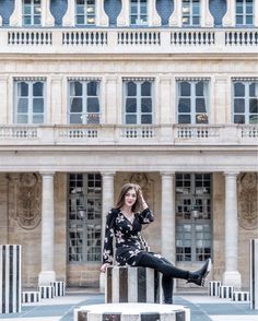 a woman standing in front of a large building with columns and pillars on the ground