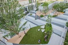 an aerial view of people sitting on benches in the middle of a courtyard with grass and trees