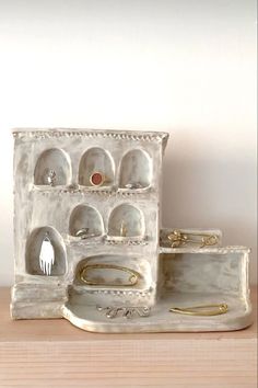 an assortment of jewelry sits on a wooden table next to a white box with gold handles