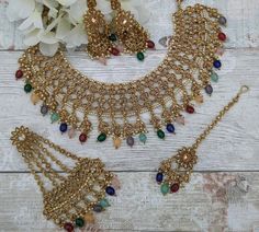 Beautiful antique gold multi coloured necklace jewellery set with earrings, jhoomer pasa & tikka headpiece. Created for my bride to wear on her henna pre wedding event.  A medium sized intricate stone perfect for bridal wear. Jhumki earring drop: 8 cm approx  Gold base filled with antique gold stones and multi beads as seen in photo/video. Bollywood Style Multicolor Jewelry Sets For Ceremonial Occasions, Bollywood Style Multicolor Ceremonial Jewelry Sets, Heavy Multicolor Kundan Jewelry Sets, Multicolor Kundan Bridal Necklace For Ceremonial Use, Heavy Kundan Multicolor Tikka, Heavy Multicolor Kundan Tikka, Heavy Multicolor Bridal Necklace For Ceremonial Occasion, Multicolor Kundan Bridal Necklace, Heavy Multicolor Kundan Bridal Necklace