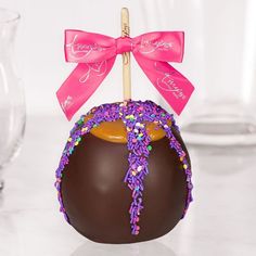 a chocolate ball with sprinkles and a pink bow on top is sitting on a table