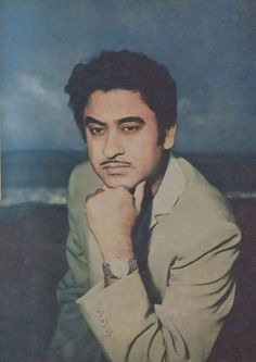 a man with his hand on his chin posing for a photo in front of the ocean