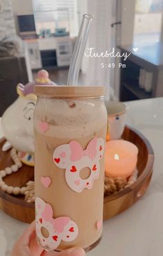 a person holding a drink in front of a plate with candles and decorations on it