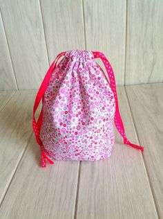 a pink and white bag sitting on top of a wooden floor next to a wall