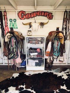 the inside of a horse stable with several saddles hanging on the wall and cow skin rug