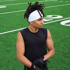 a young man with dreadlocks and gloves standing on a football field