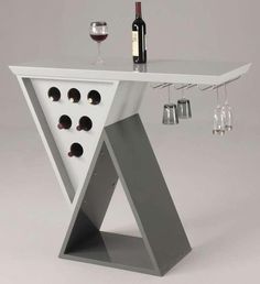 a white table with wine glasses and bottles on it, in front of a bottle rack