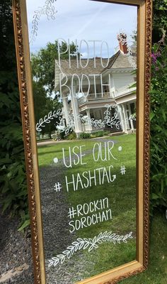 a mirror that is on the ground in front of some grass and bushes with words written below it