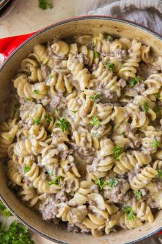 a skillet filled with pasta and meat sauce on top of a red table cloth