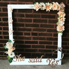 a white frame with flowers and the words she said yes