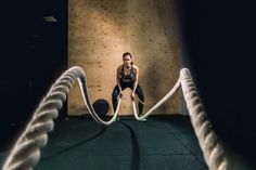 a woman is doing exercises with ropes in the gym