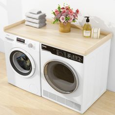 a washer and dryer sitting on top of a wooden counter next to flowers