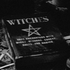 a black and white photo of a book on the ground with witches written on it