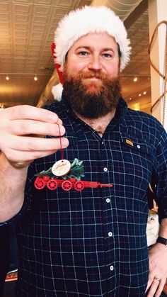 a bearded man wearing a santa hat and holding a candy cane with a christmas decoration on it