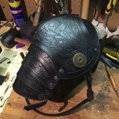 a helmet sitting on top of a wooden table next to other tools and supplies in a workshop