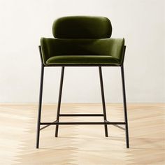 a green chair sitting on top of a hard wood floor next to a white wall