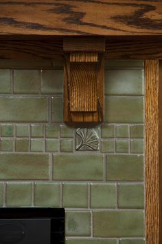 a black microwave sitting on top of a counter next to a green tiled backsplash