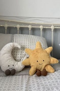 two stuffed animals sitting on top of a bed next to pillows and pillowcases