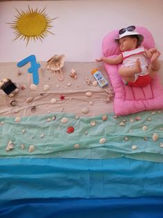 a baby laying on top of a pink chair next to an ocean themed wallpaper