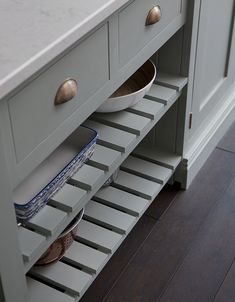 a kitchen cabinet with two bowls on the bottom shelf and one bowl in the middle drawer