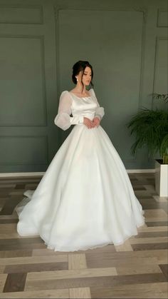 a woman in a white dress is standing on the floor with her hands behind her back