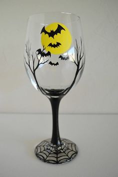 a wine glass decorated with bats and trees