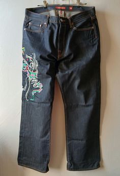 36x32 RARE Ed Hardy jeans. Luxury street wear by Christian Audigier. Y2K style baggy denim with a dark wash featuring a panther with a snake wrapped around him. Panthers heads on both back pockets. A beautiful rare pair of denim that looks almost new. You will see some tear at back bottom of the jean cuffs. See pictures for the small hole there is.  Measurements in inches: 43.5 length. Waist to bottom of leg opening 13 Rise. Waist band to crotch  10 Knee 12.5 Thigh 36 waist 32 inseam Ed Hardy Jeans, Baggy Denim, Christian Audigier, Ed Hardy, Street Chic, Y2k Style, Tattoo Style, Luxury Streetwear, Panther