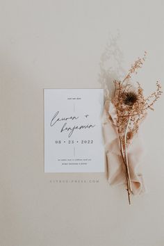 the wedding stationery is laid out with dried flowers