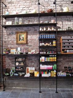 a brick wall with shelves filled with jars and condiments on each shelf in front of it