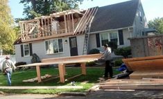 two men are working on the roof of a house that's being built in front of it