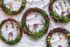 moss covered wreaths with mushrooms and plants in them on a white tablecloth background